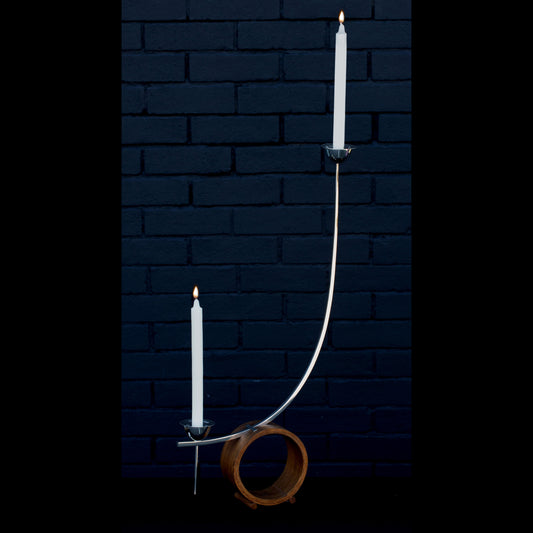 Two candles made out of solid 925 sterling silver suspended in perfect harmony on an English oak circular base to allow transparency and balance. 